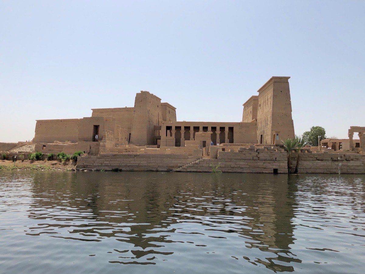 Philae temple columns and pylon reflected in still Nile water